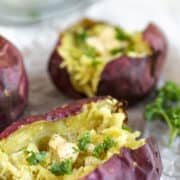 An overview shot of a baked sweet potato topped with butter and parsley