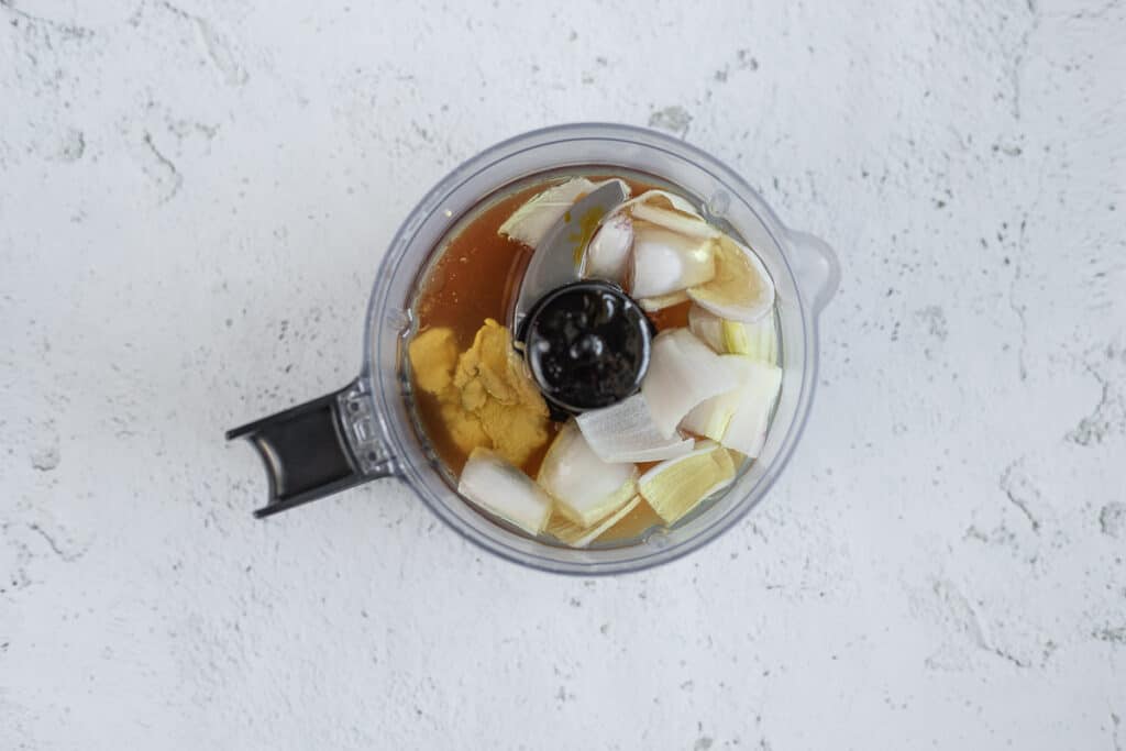 An overview shot of a food processor with the ingredients for apple cider vinegar dressing