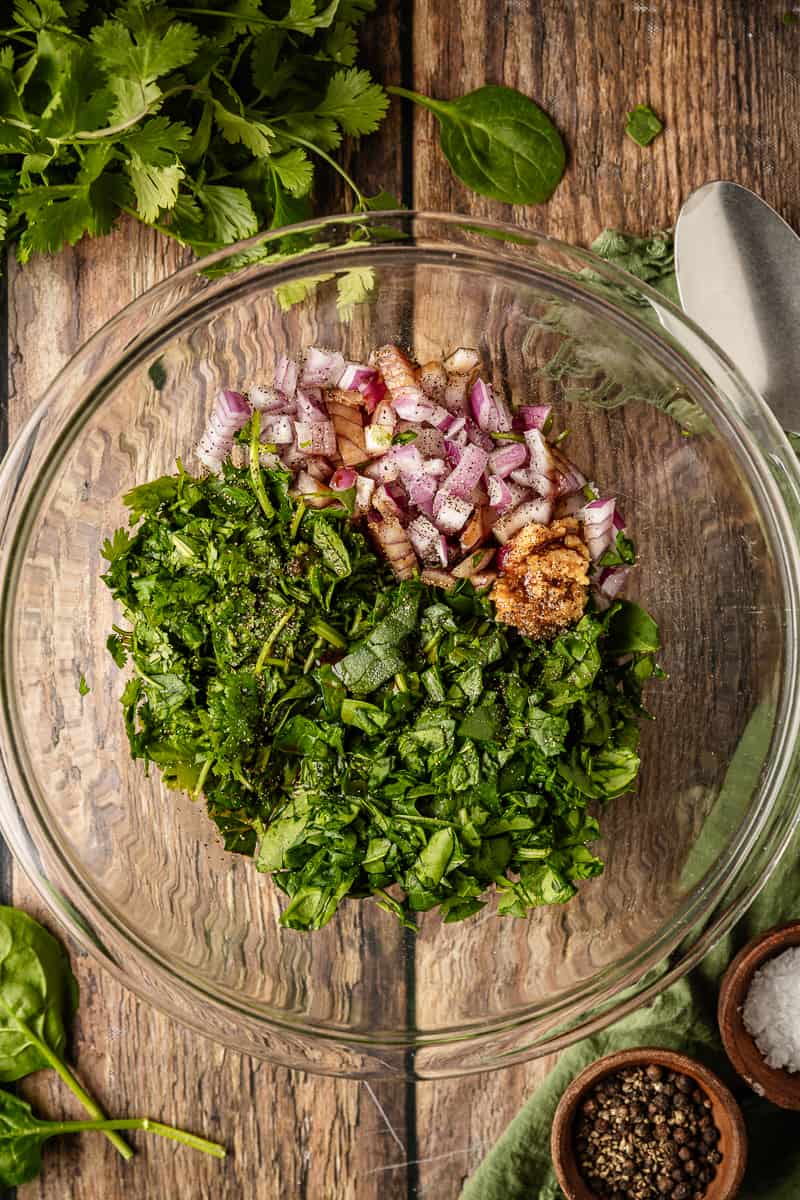 An overview shot of the ingredients for asian meatballs in a glass mixing bowl