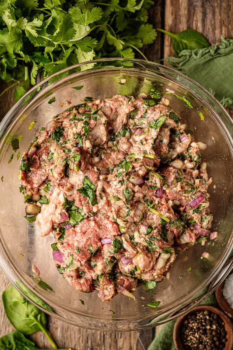 An overview shot of asian meatballs meat mixture in a glass mixing bowl