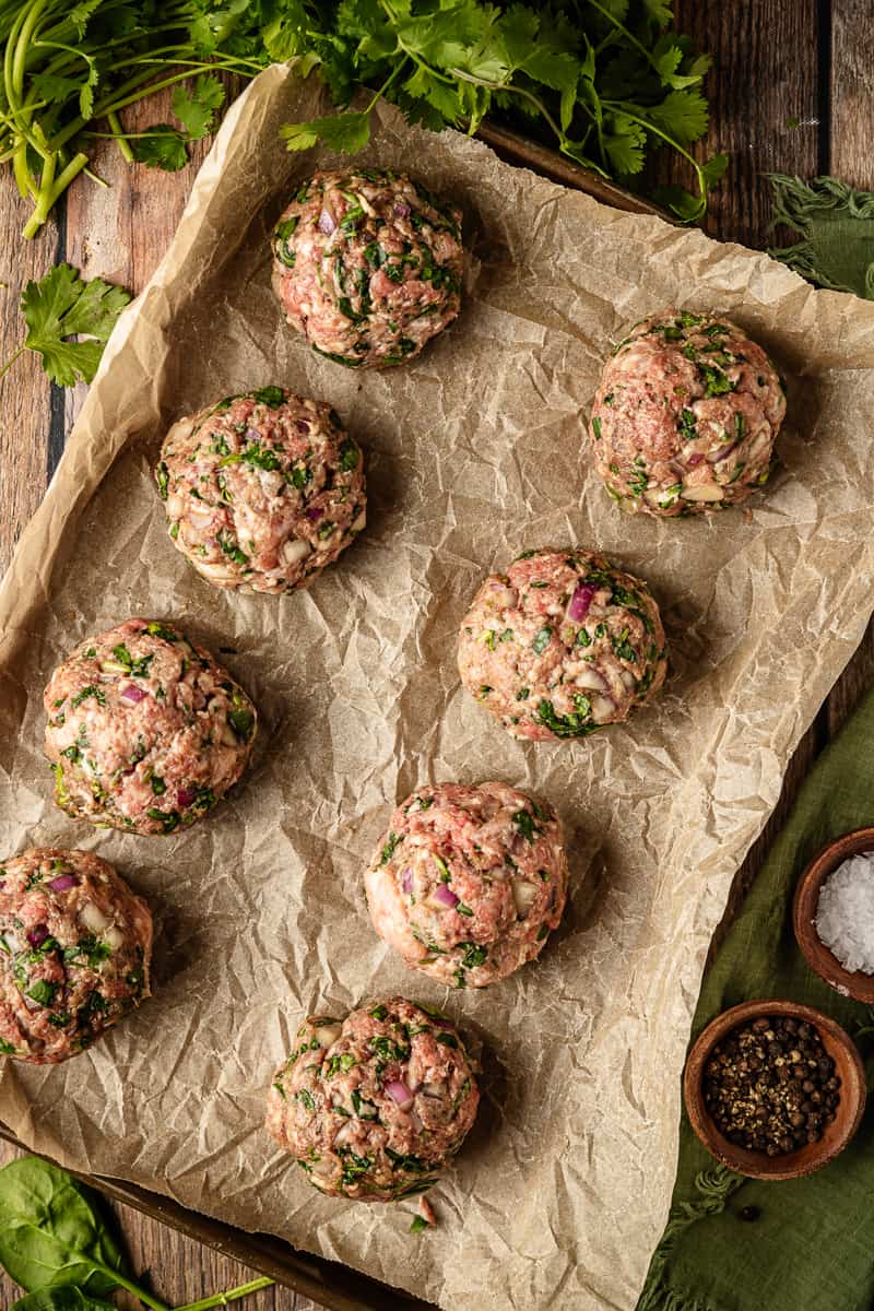 An overview shot of 8 jumbo meatballs on a baking sheet