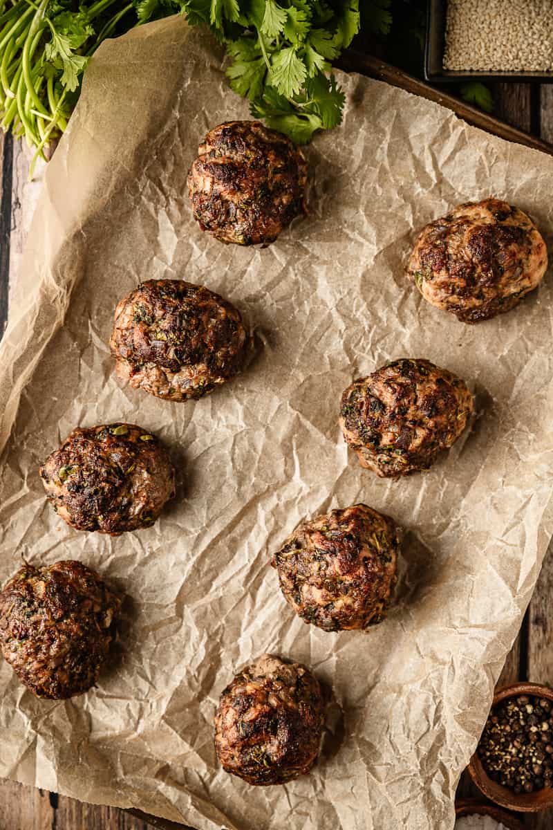 An overview shot of 8 jumbo baked meatballs on a baking sheet