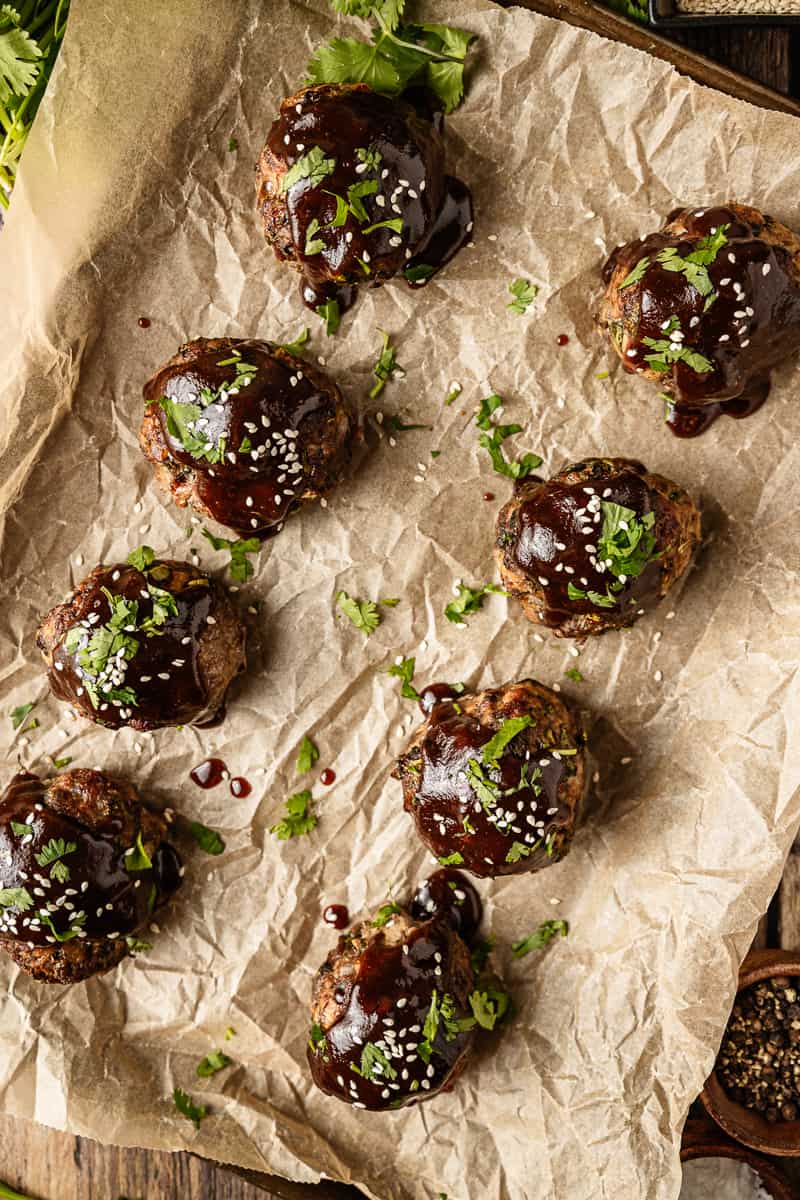 An overview shot of 8 jumbo meatballs with a whole30 teriyaki glaze on a baking sheet