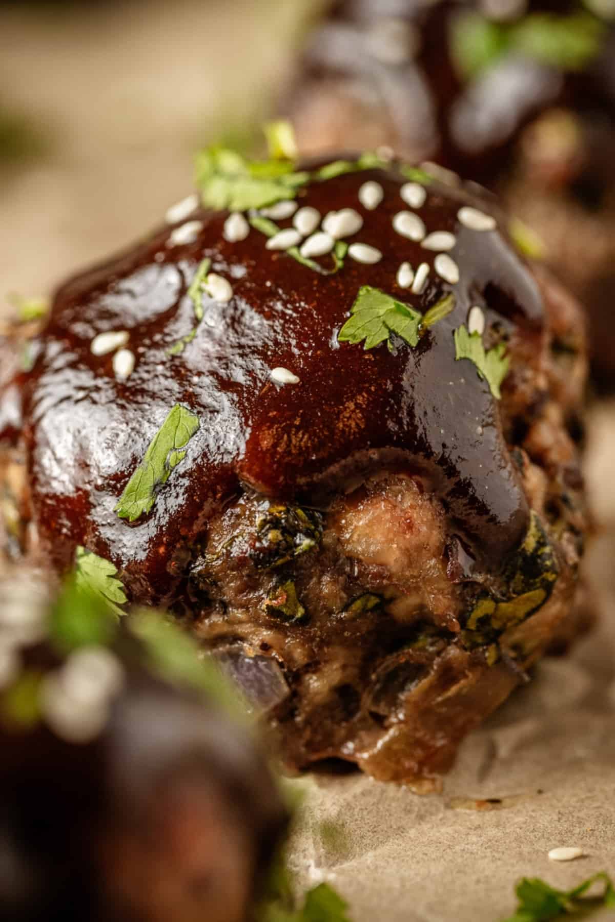 A close up view of a Whole30 meatball with asian sticky sauce on a baking sheet