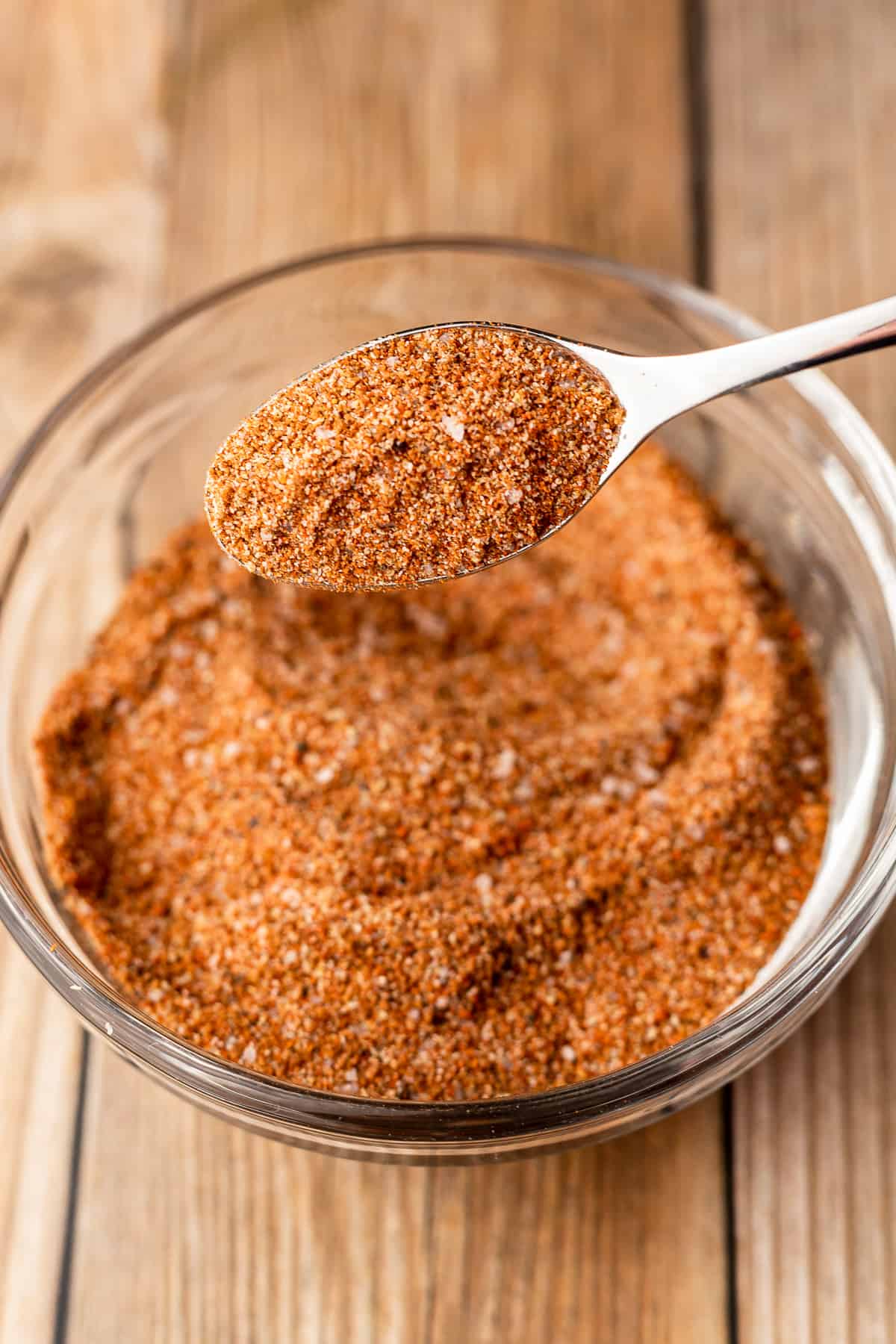 BBQ chicken rub in a small glass bowl with a spoonful of the rub on a silver spoon.