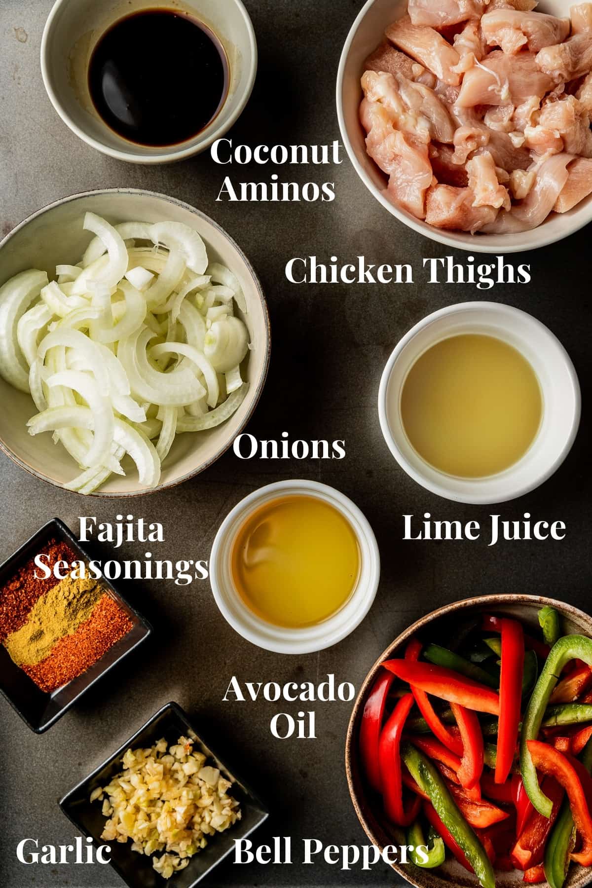 An overview shot of the ingredients needed for fajitas in separate bowls on a black background