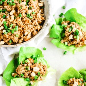 A top view of a bowl of chicken lettuce wrap filling and lettuce wraps