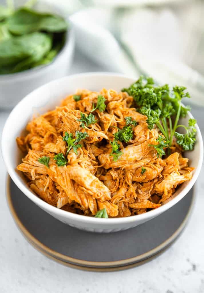 A bowl of shredded buffalo chicken topped with parsley