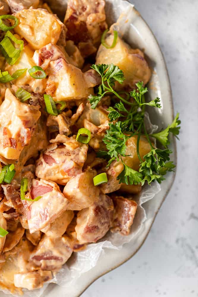 An overview shot of Whole30 Buffalo Ranch Potato Salad topped with parsley in a grey bowl