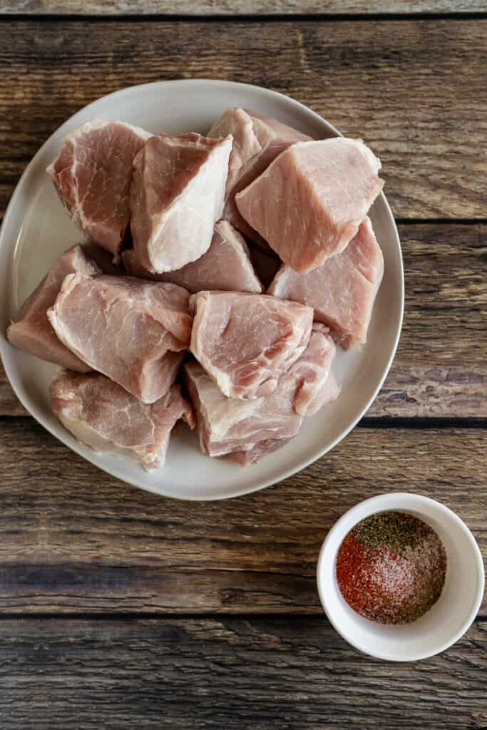 An overview shot of pork next to seasonings for carnitas