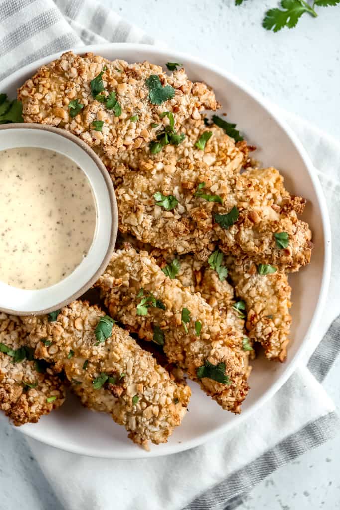 An overhead shot of air fryer chicken tenders on a plate next to Whole30 ranch