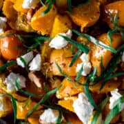 A close up view of golden beet salad topped with fresh herbs.