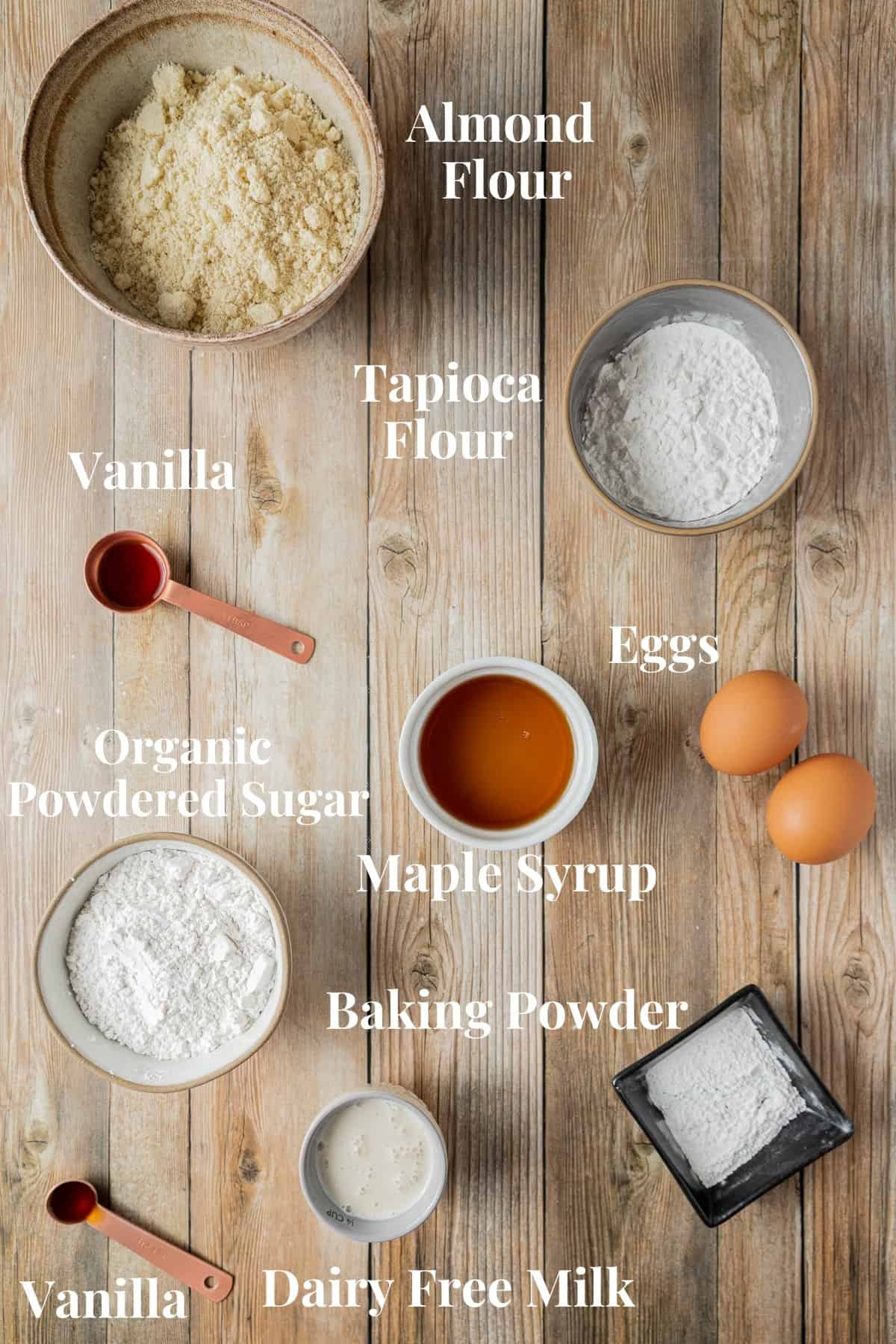 An overhead shot of the ingredients needed for donuts in small bowls with text.