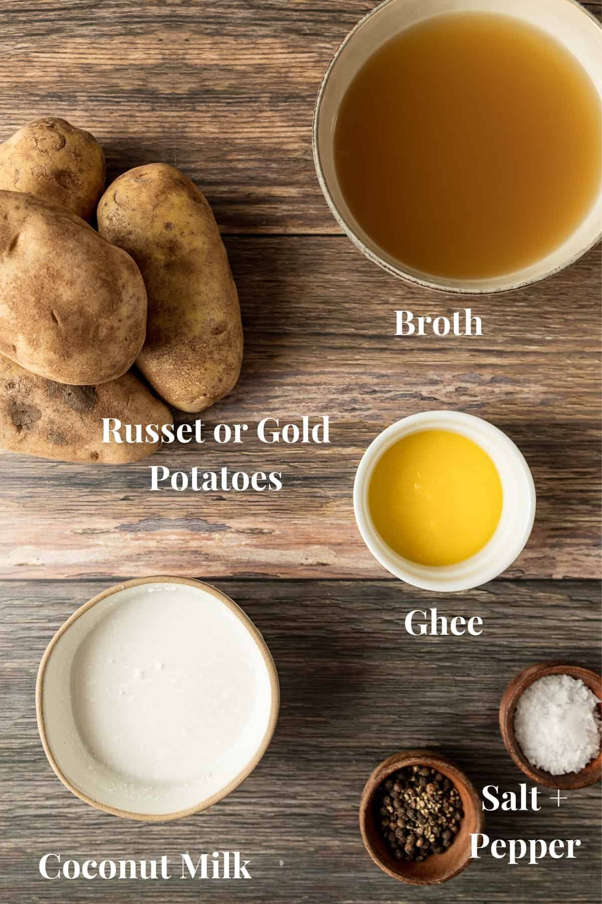 An overview shot of the ingredients needed for mashed potatoes in bowls on a wood background.