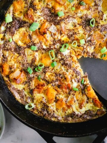 A kabocha squash frittata with a slice taken out next to a plate of frittata