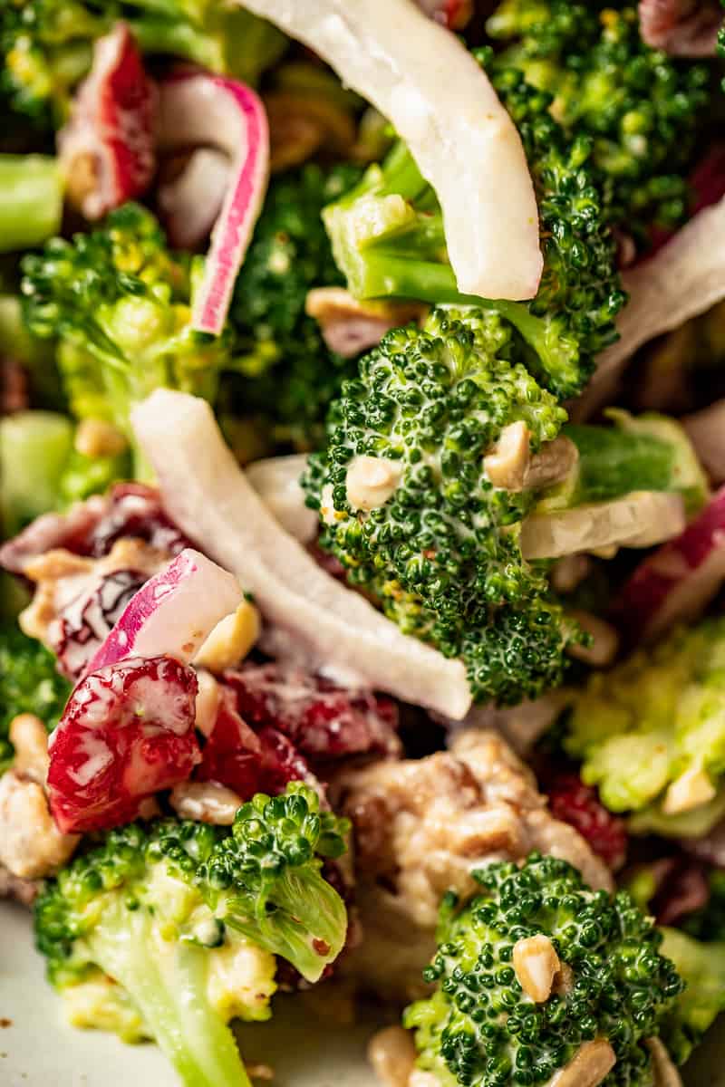 A closeup view of creamy paleo broccoli salad with onions, cranberries, and sunflower seeds
