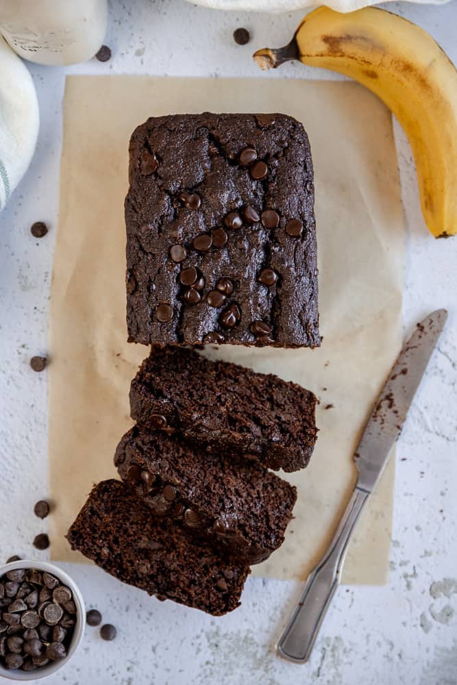 An overview of chocolate chip banana bread slices next to a banana and chocolate chips
