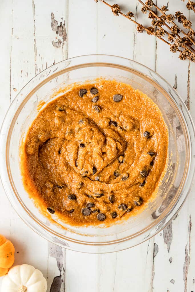 An overhead shot of pumpkin muffin batter with almond flour and chocolate chipss on a white background