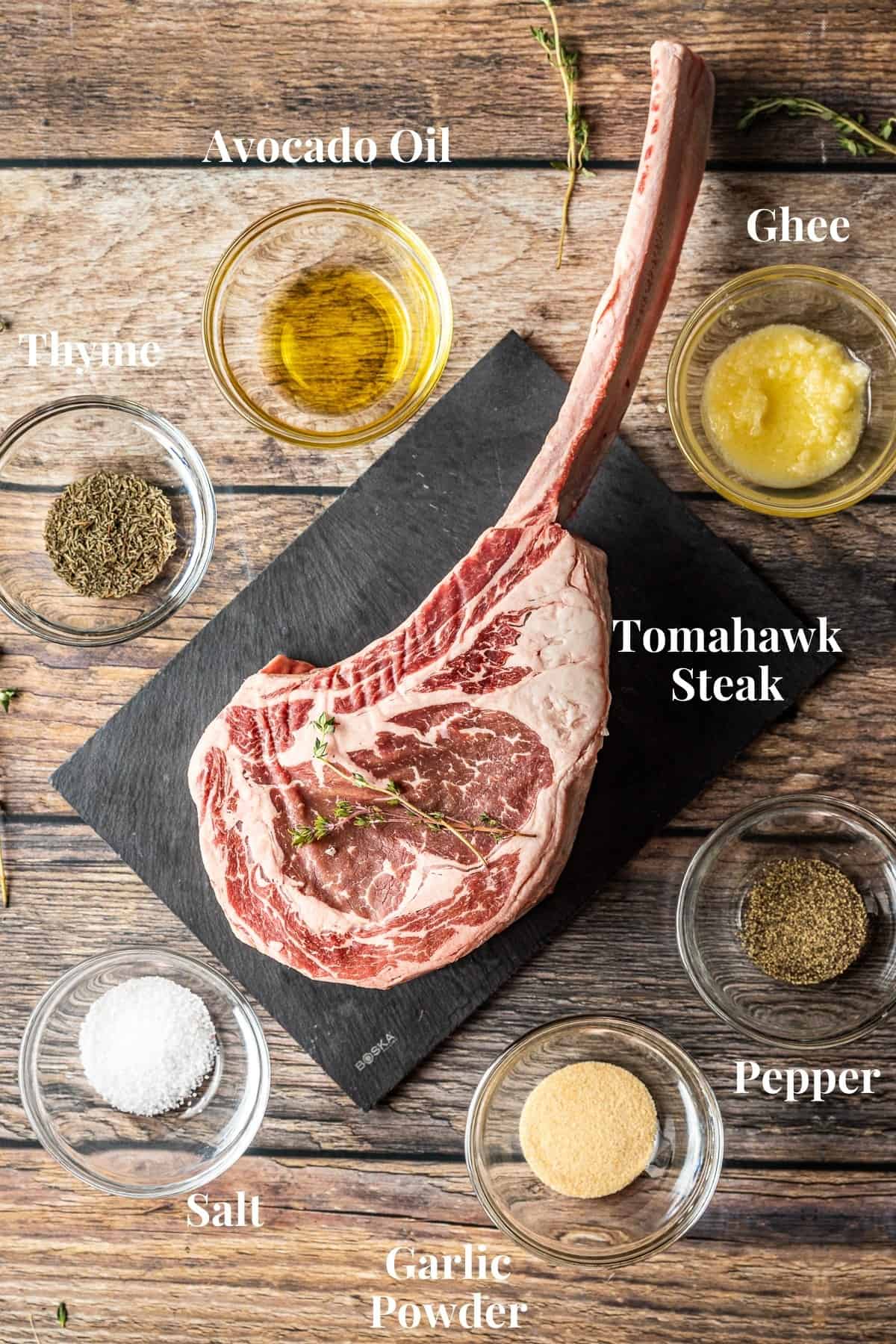 An overview shot of the ingredients needed to smoke a tomahawk steak on a wood background.