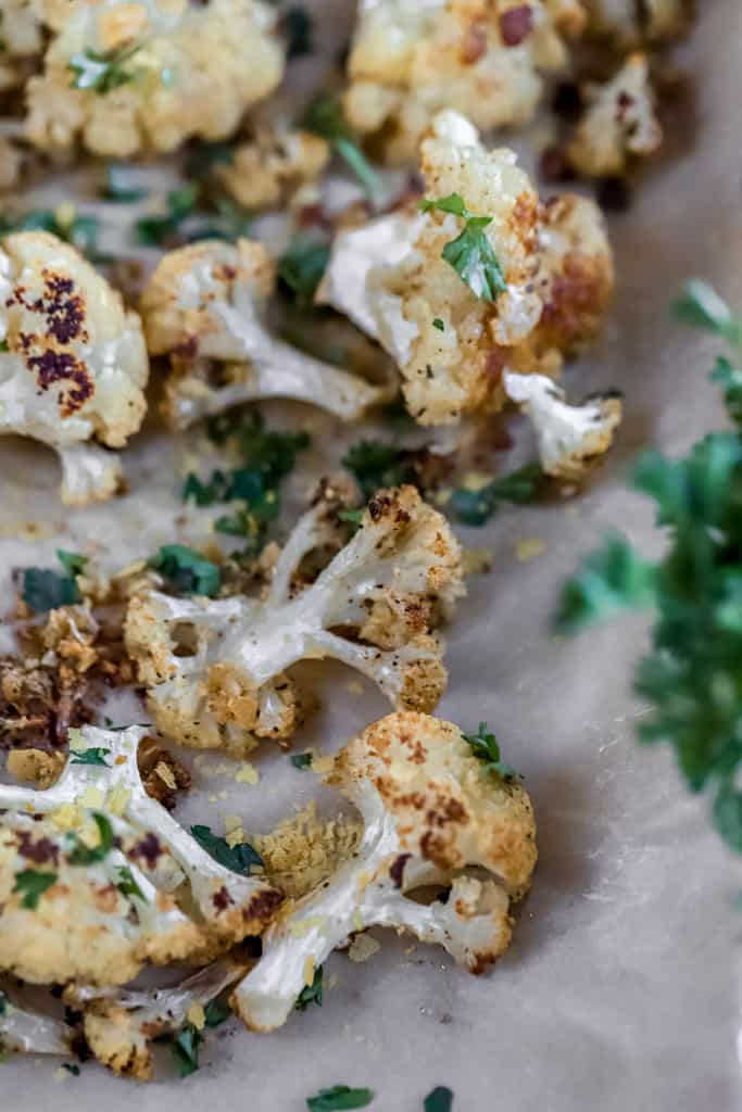 A pan of roasted cauliflower topped with chopped parsley.