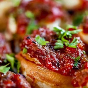 A close up of a bacon wrapped scallop with red pepper relish.