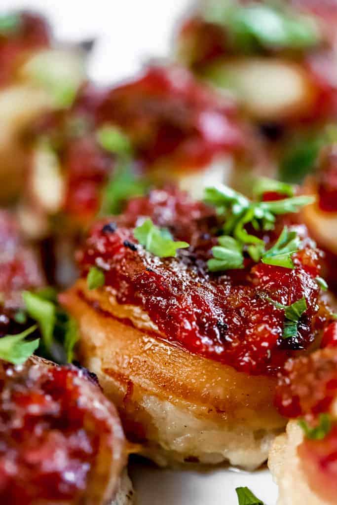 A close up of a bacon wrapped scallop with red pepper relish.