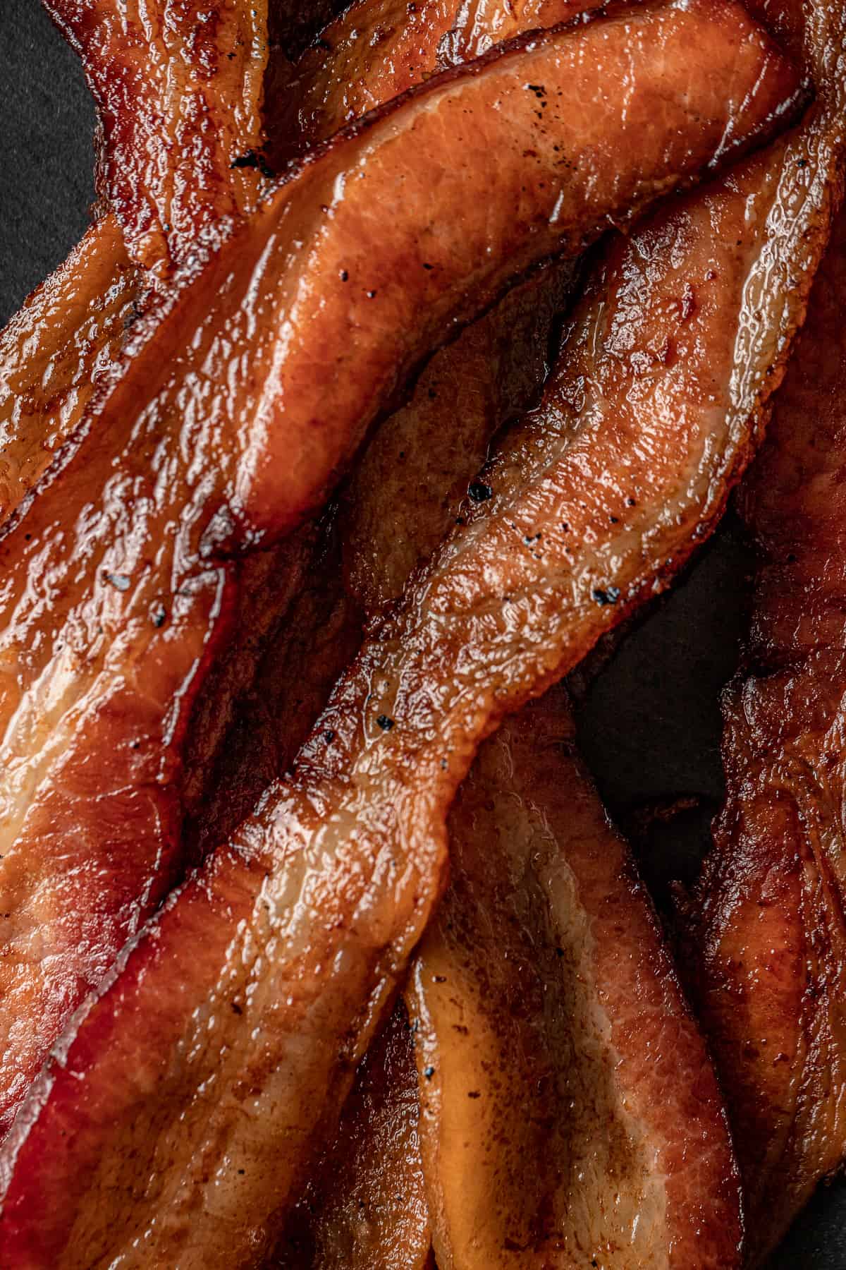 A closeup shot of smoked bacon on a bkack background.