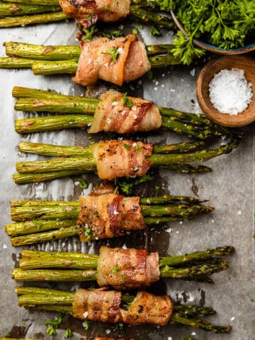 An overhead shot of a pan full of grilled bacon wrapped asparagus bundles.
