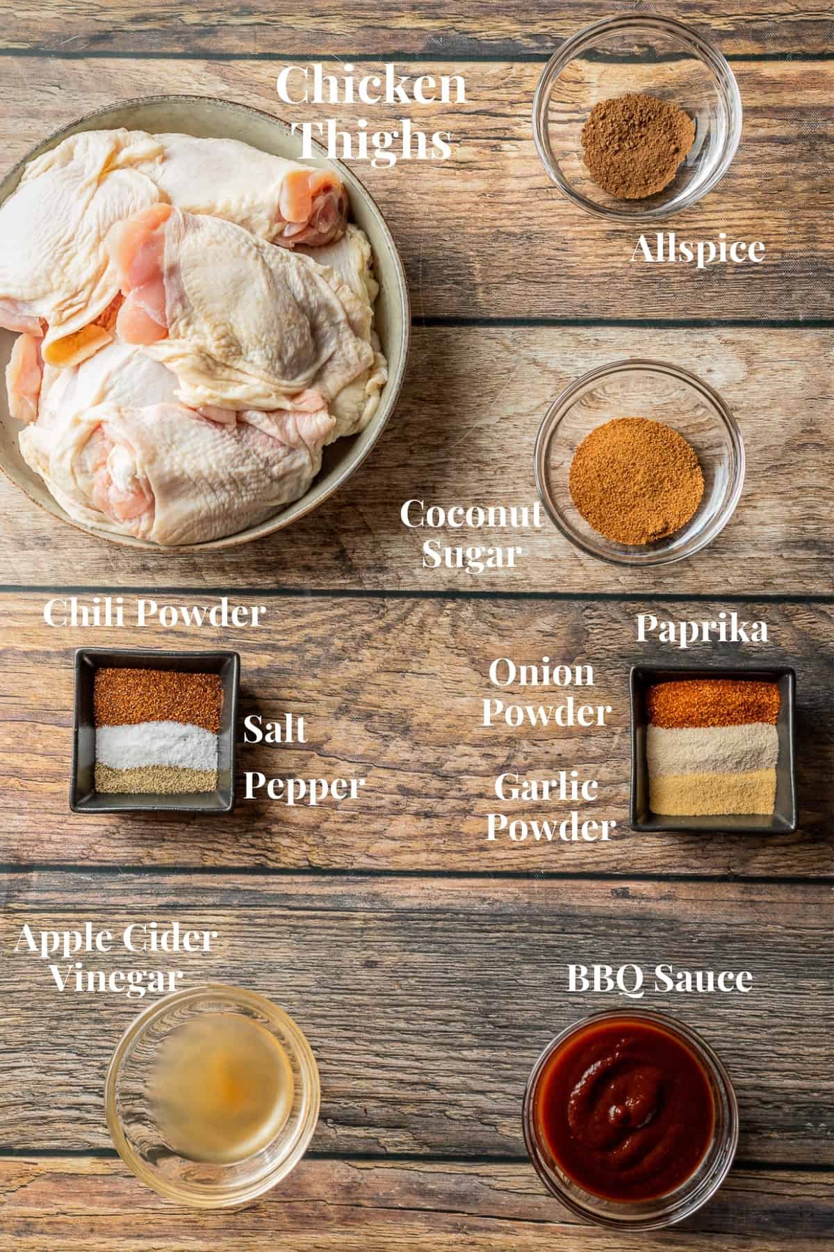 An overview shot of the ingredients needed for smoked chicken on a wood background.