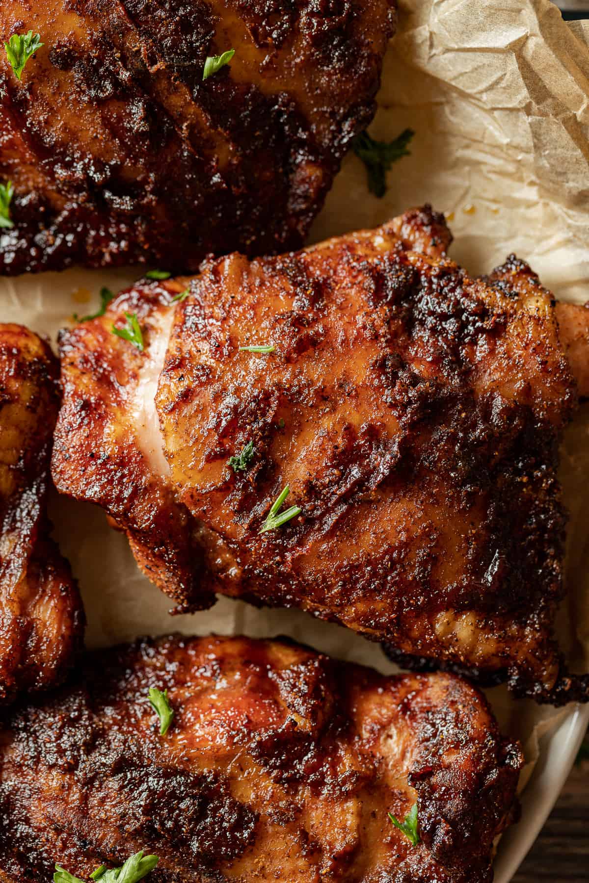 An overview shot of smoked chicken thighs plated and topped with parsley.