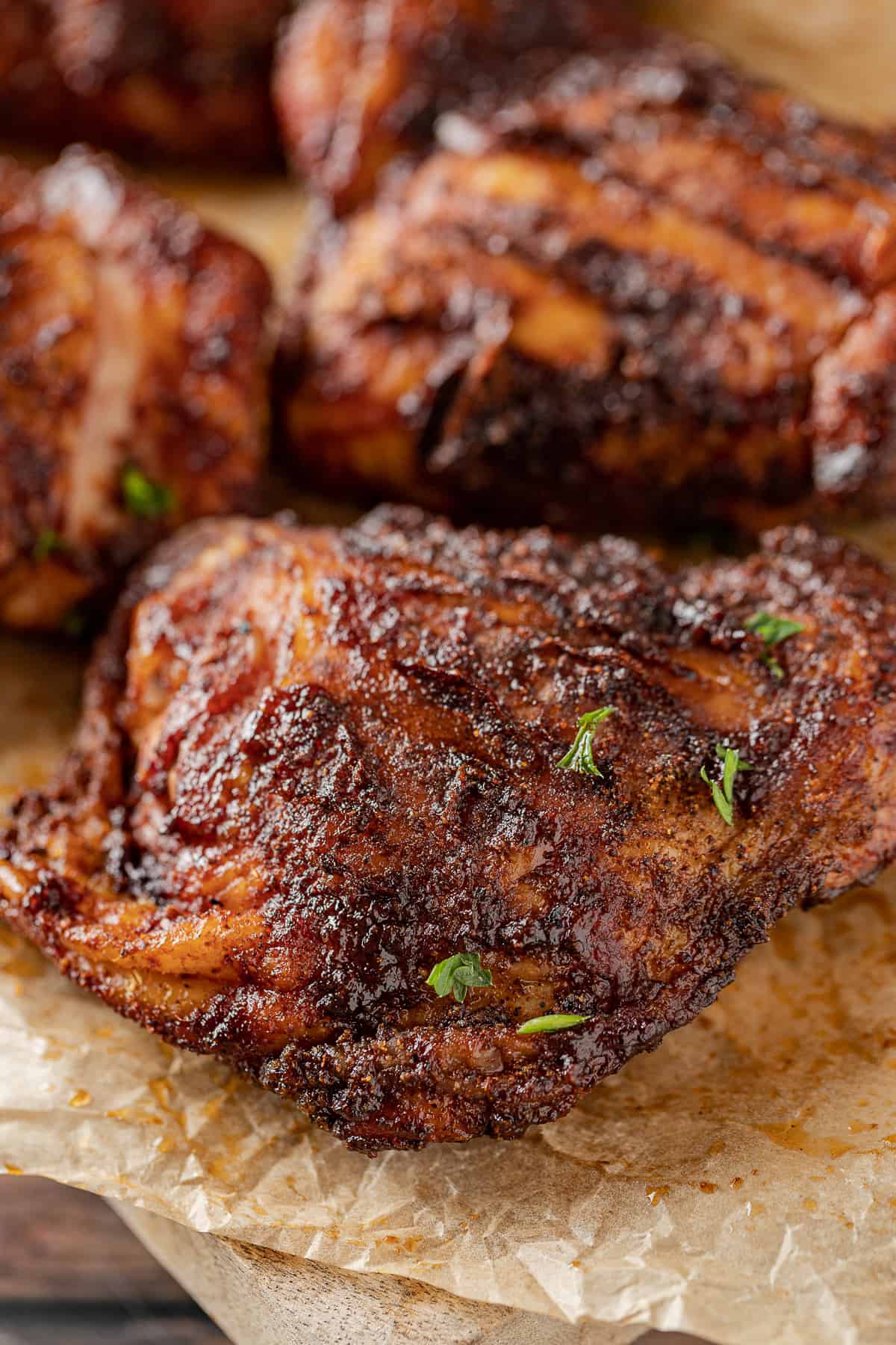 A close up view of a smoked chicken thigh topped with BBQ sauce.