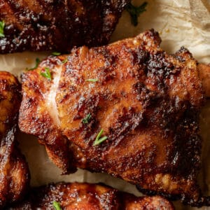 An overview shot of smoked chicken thighs plated and topped with parsley.