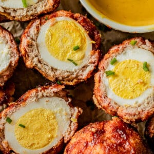 An overview shot of smoked keto scotch eggs cut in half and topped with green onions.