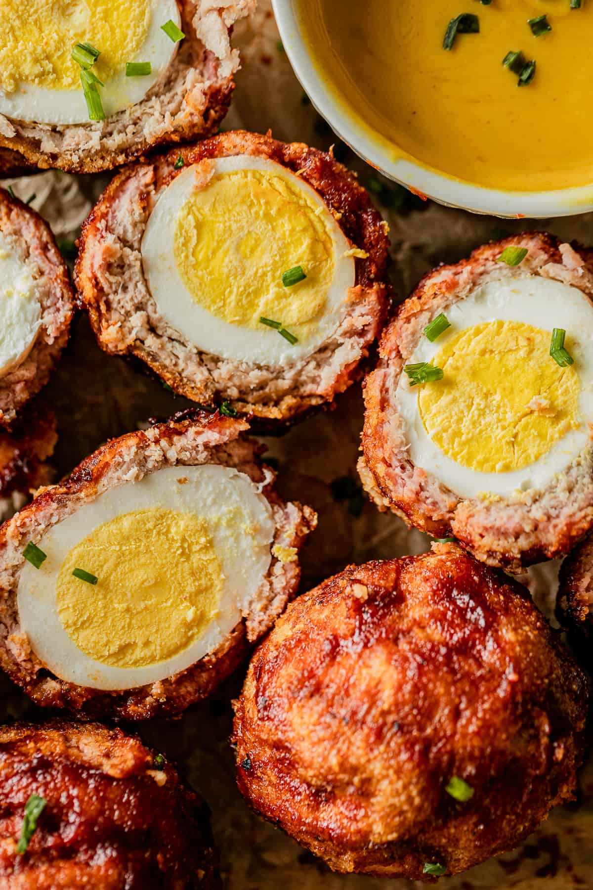An overview shot of smoked keto scotch eggs cut in half and topped with green onions.