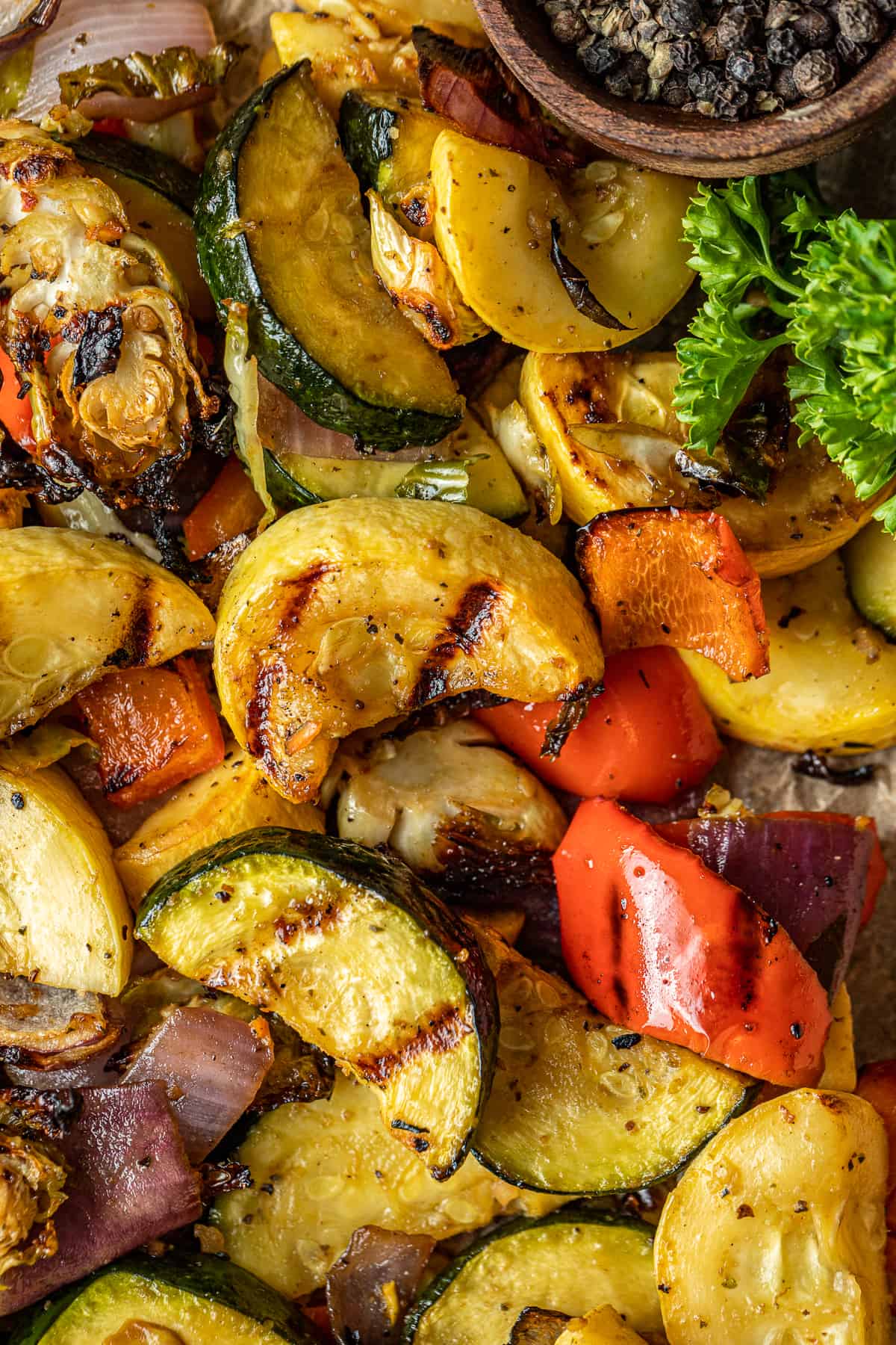 A closeup overview shot of smoked vegetables on a baking dish lined with parchment paper.