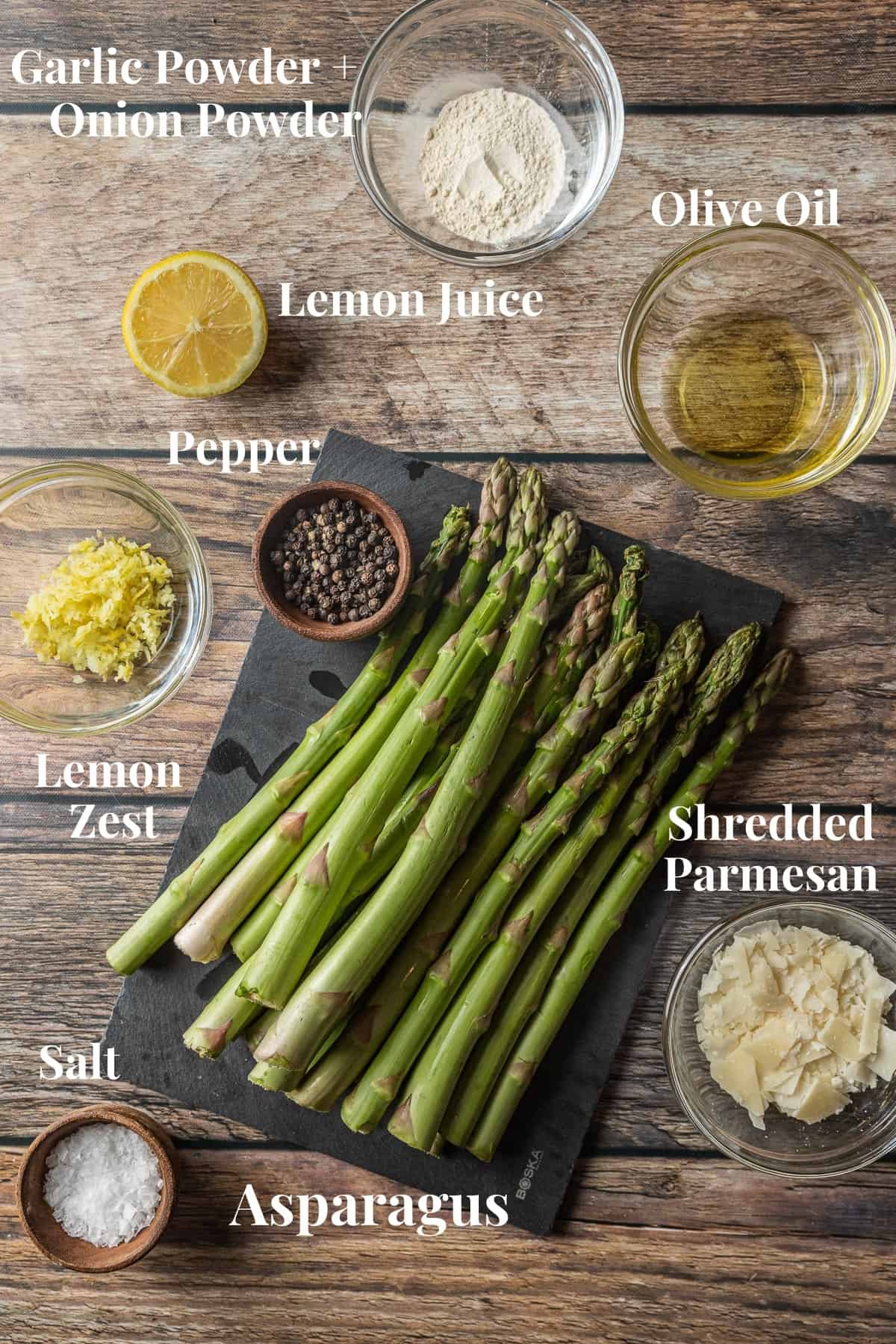 An overview shot of the ingredients needed for grilled asparagus with lemon on a wood background.
