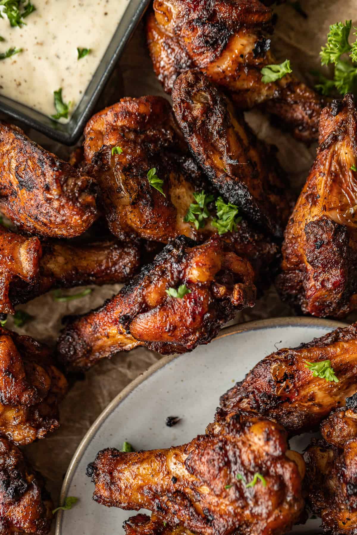 An overview shot of dry rub chicken wings topped with parsley and served with ranch.