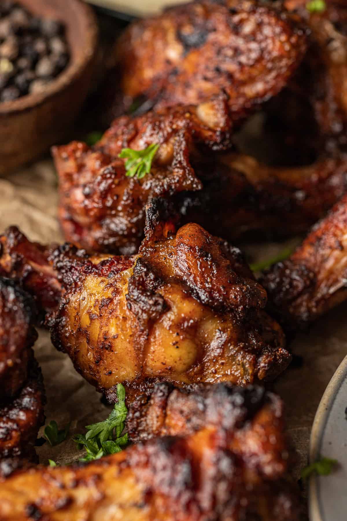 A close up shot of crispy traeger smoked chicken wings topped with parsley on parchment paper.