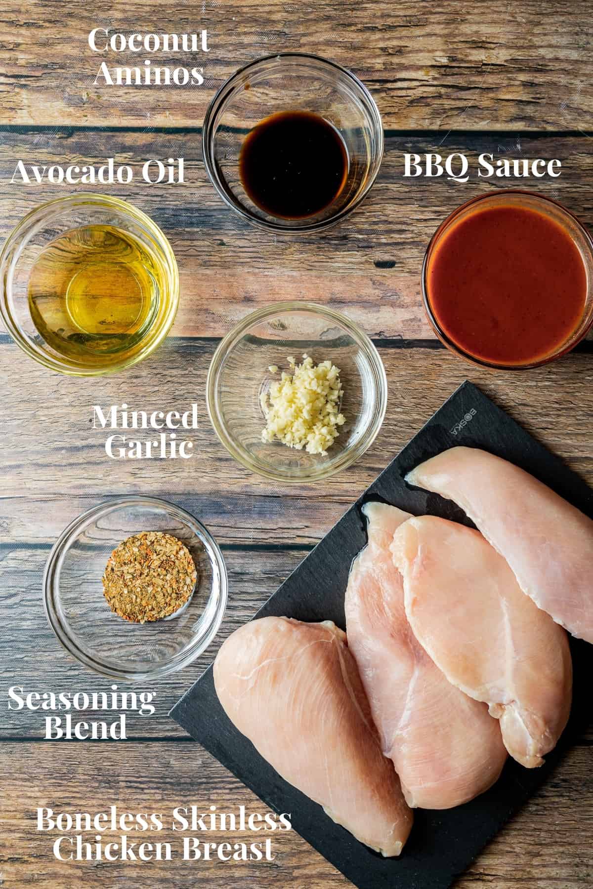 An overview shot of the ingredients needed for smoked BBQ chicken on a wood background.