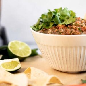 A bowl of whole30 salsa topped with cilantro on a cutting board next to chips