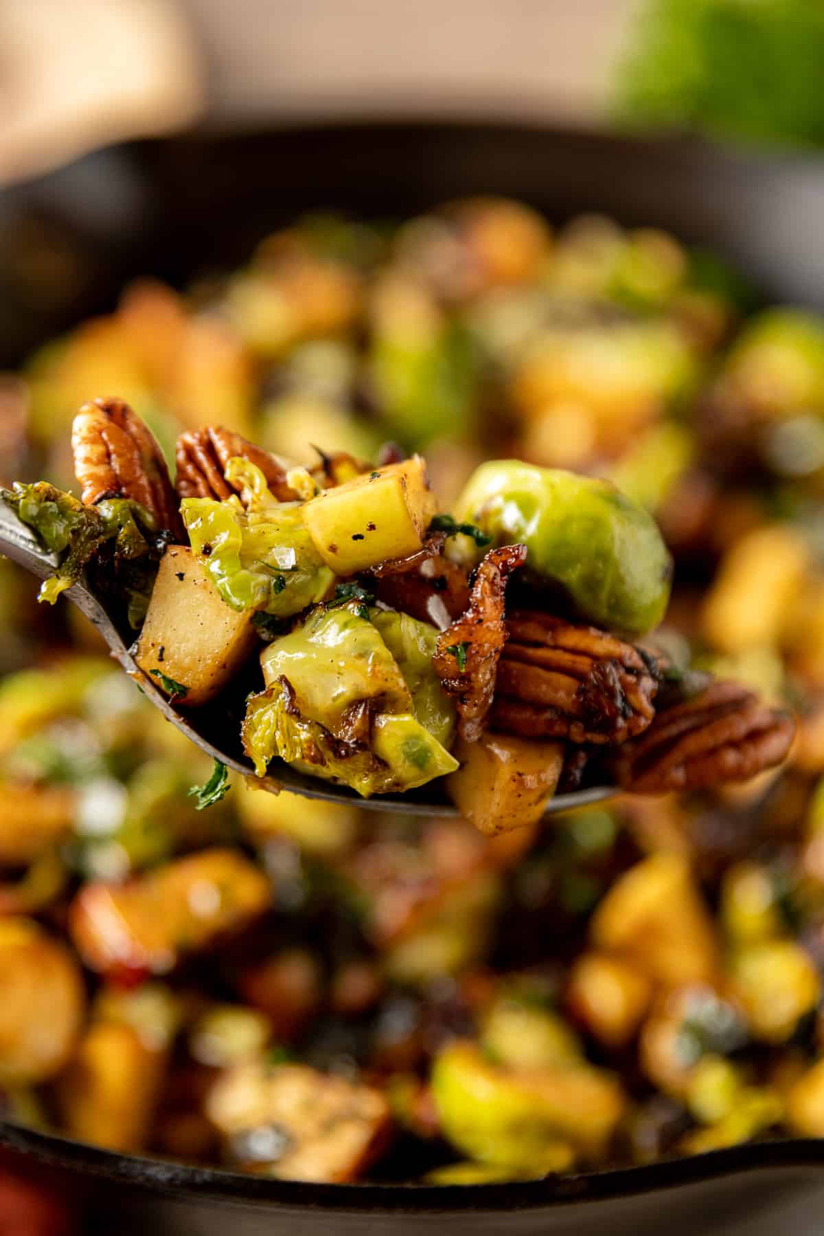 A fork full of brussels sprouts with apples, pecans, and balsamic glaze.