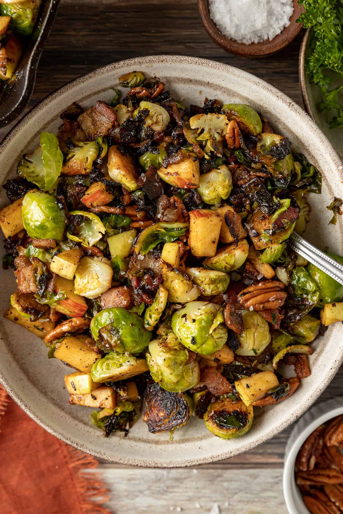An overview shot of a bowl of brussel sprouts with apples and pecans topped with balsamic glaze.