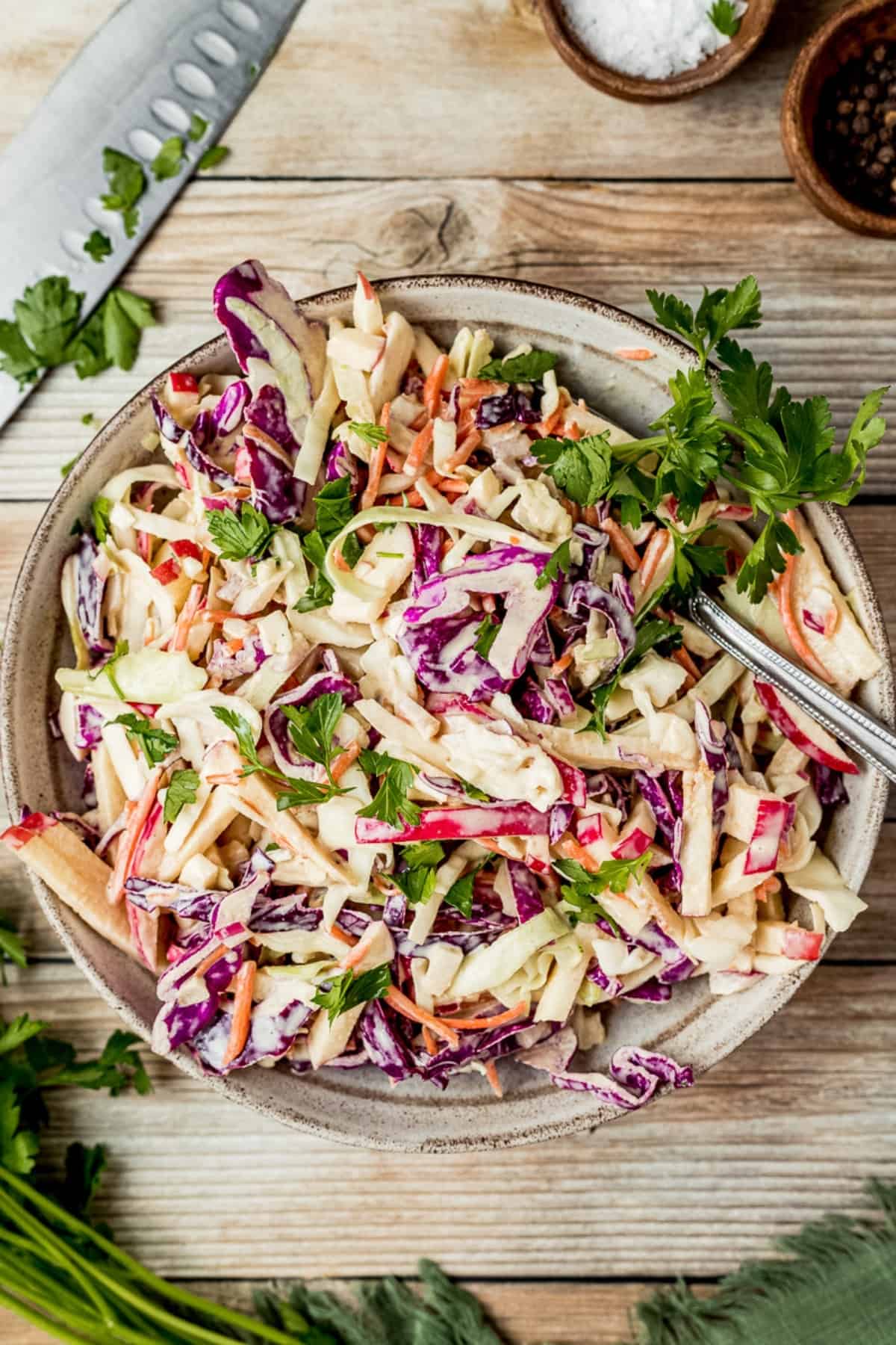 An overview shot of a bowl of Whole30 coleslaw on a wood background