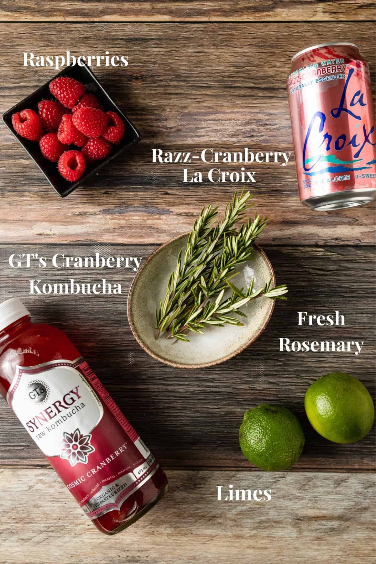 An overview photo of the ingredients needed for a Whole30 cranberry raspberry mocktail on a wood background.