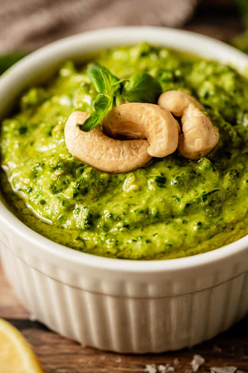 An upclose shot of Whole30 pesto topped with cashews and olive oil in a white bowl