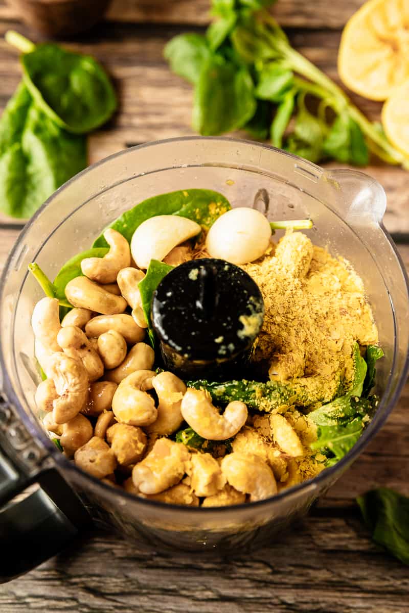 A food processor bowl filled with the ingredients for Whole30 pesto