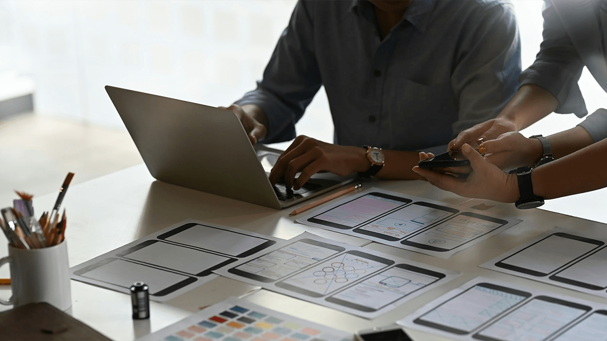 Colleagues planning with a laptop and many paper sheets on table